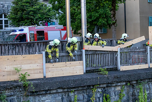 Mitglieder der Feuerwehr beim Anbringen von Holzbalken entlang der Ill. 