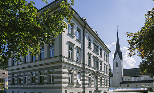 Volksschule Sebastianplatz von außen, im Hintergrund der Kirchturm