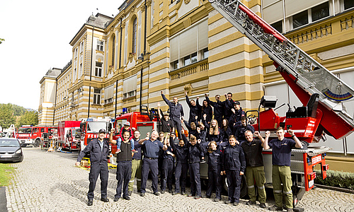 Eine Gruppe der Feuerwehr posiert vor einem Feuerwehrauto