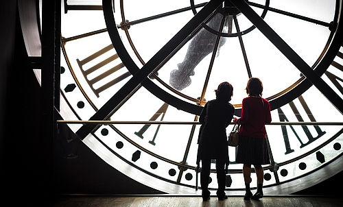 Zwei Personen stehen vor einer großen Uhr.