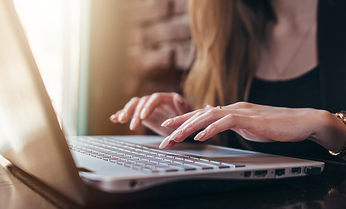 Eine Frau tippt auf der Tastatur eines Laptops.