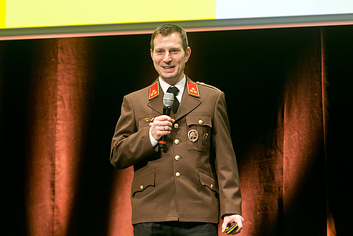 Kommandant der Feuerwehr Altenstadt Marcel Frick steht auf der Bühne und spricht in ein Hand-Mikrofon.