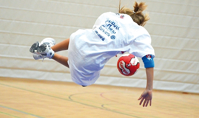 Person spielt Handball in einer Turnhalle