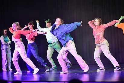 Eine Gruppe von Jugendlichen steht auf der Bühne und tanzt.