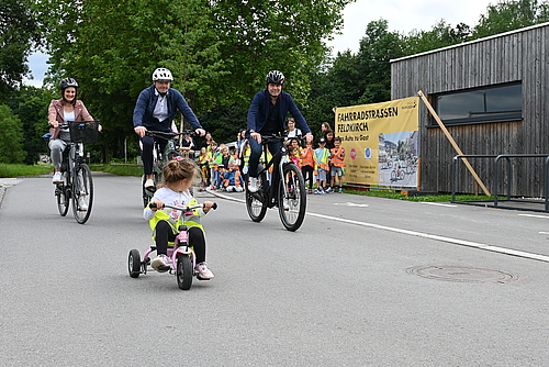 Eine Mitarbeiterin der Verwaltung, Stadtrat Thomas Spalt und Bürgermeister Manfred Rädler fahren nebeneinander auf der Fahrradstraße. Vor ihnen fährt ein kleines Mädchen auf ihrem Dreirad.