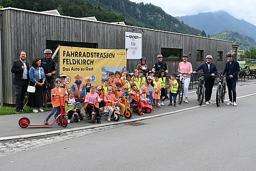 Politische Vertreter:innen, Vertreter der Stadtpolizei und die Kinder des Kindergartens Kirchgasse stehen zusammen vor dem Gebäude des TSV Altenstadt.