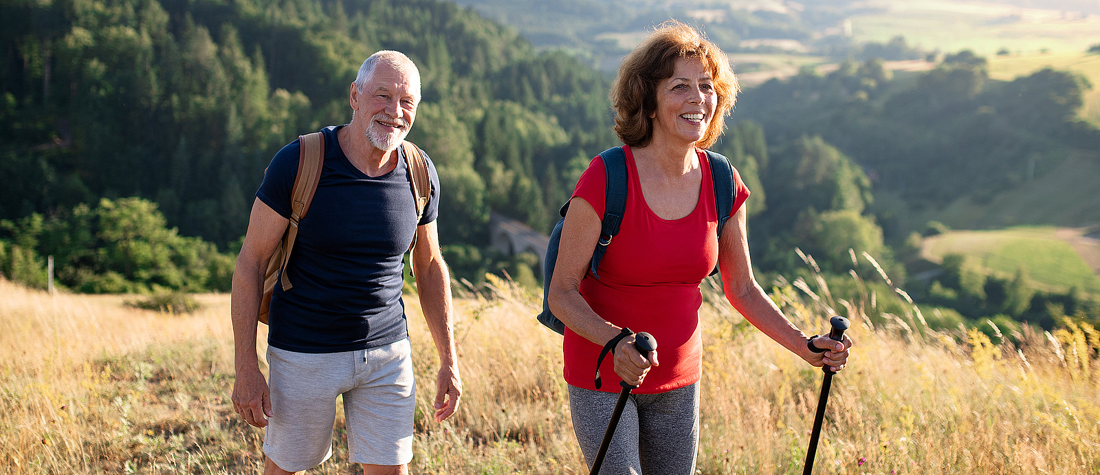 Ein älterer Herr und eine ältere Frau wandern durch die Natur.