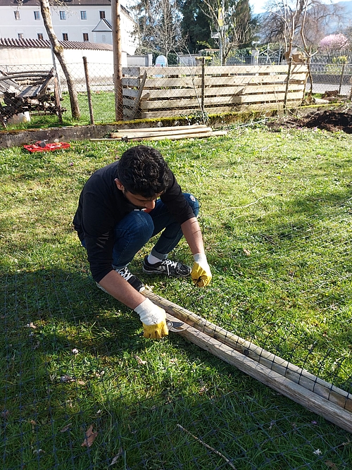 Ein Flüchtling arbeitet an einem Gartenzaun. 