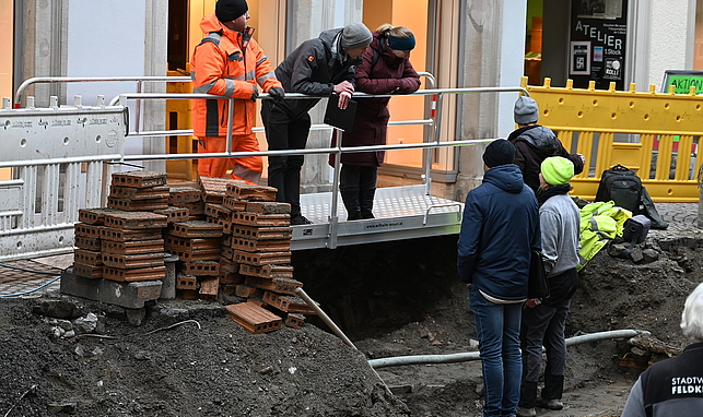 Männer und Frauen begutachten die Baustelle in der Schmiedgasse.
