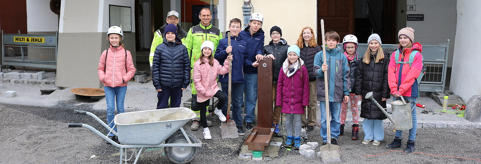 Kinder stehen mit Bauarbeitern in der Neustadt beim neuen Brunnen.