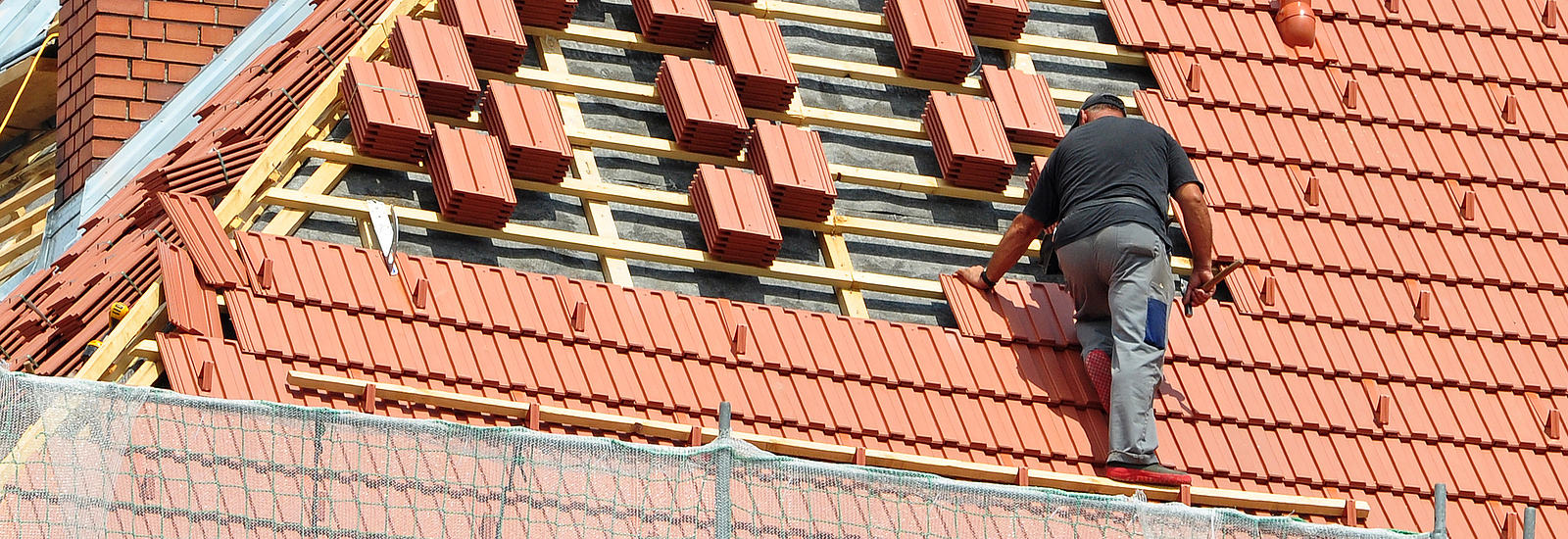 Ein Arbeiter bedeckt ein Dach mit Ziegeln.