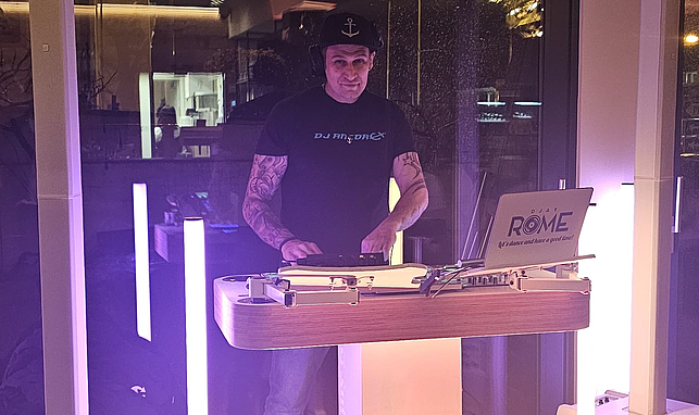 Ein Mann steht an einem DJ-Mischpult.