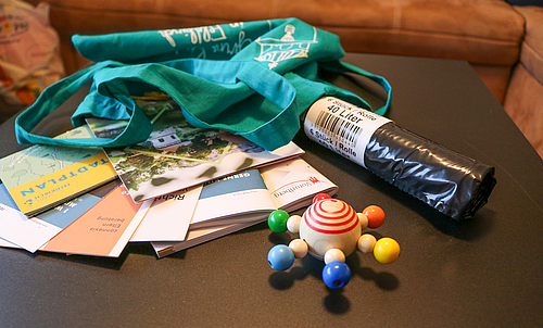 Mehrere Unterlagen, eine Rolle Restmüllsäcke und ein Spielzeug liegen auf einem Tisch.