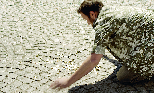 Ein Mann hebt Münzen vom Boden auf.