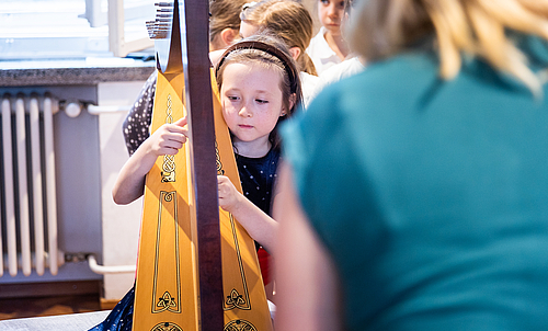 Ein kleines Mädchen spielt Harfe.